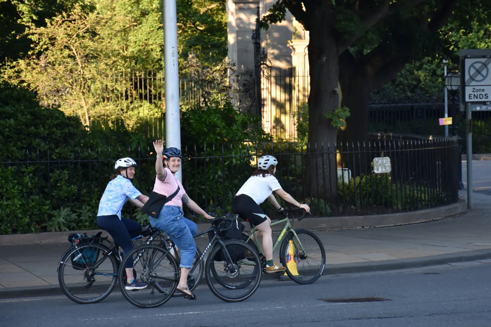 A cyclist waving at the camera while cycling past